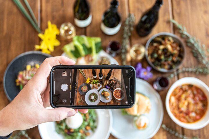 Person using photo to photograph a table covered in dishes prepared by cooking with wine at Brooks Wine in Willamette Valley, Oregon. 