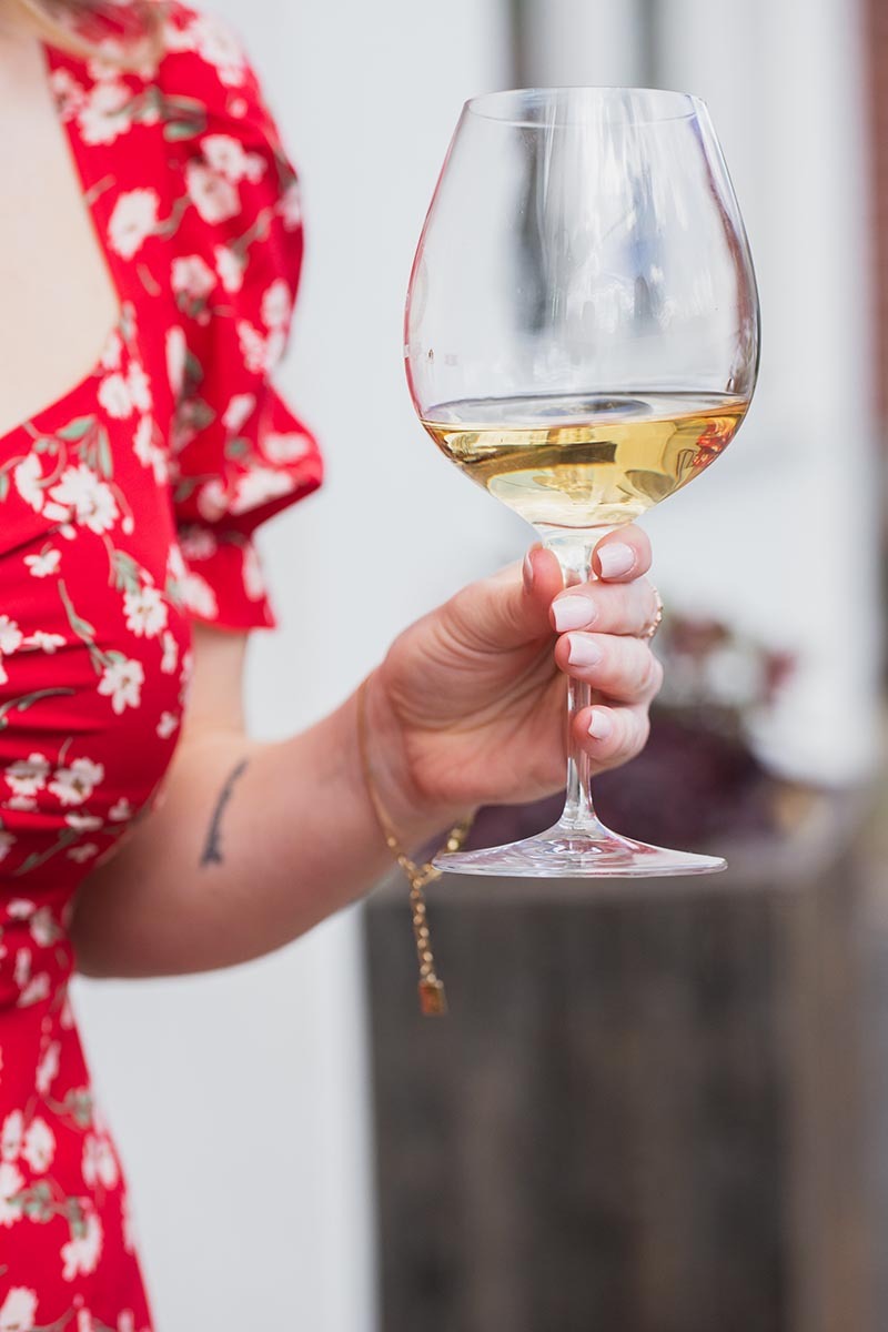 A woman in red summer dress holding a glass of sparkling wine: one of the most popular wines for women!