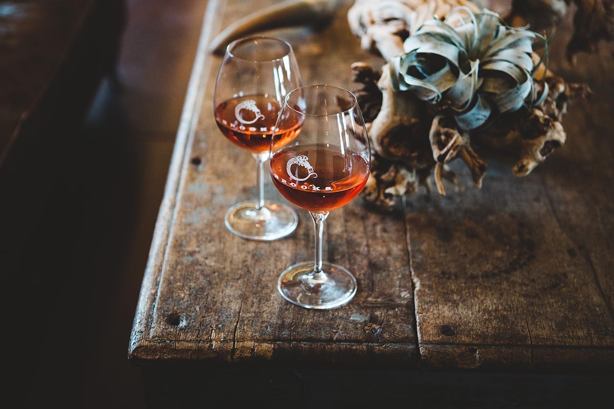 Wine glasses filled with rose wine on a rustic wooden table at a winery tasting room near Portland, Oregon.
