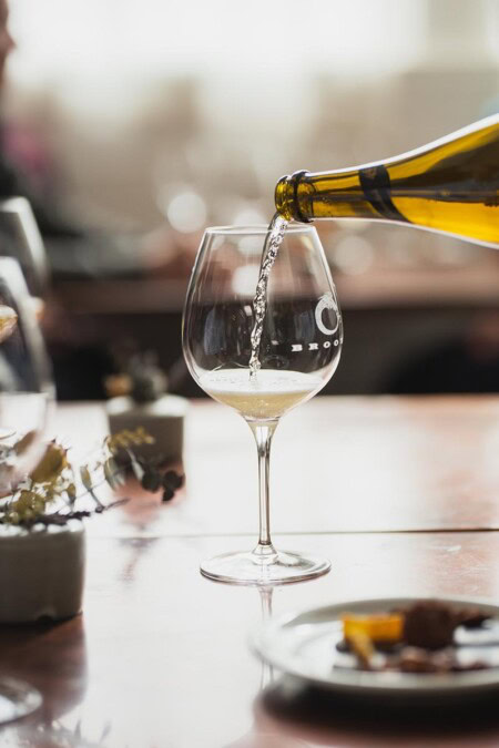 A bottle of extended tirage sparkling Riesling is poured into a stemmed wine glass at Brooks Wine, the top producer of single-vineyard Riesling in the United States.