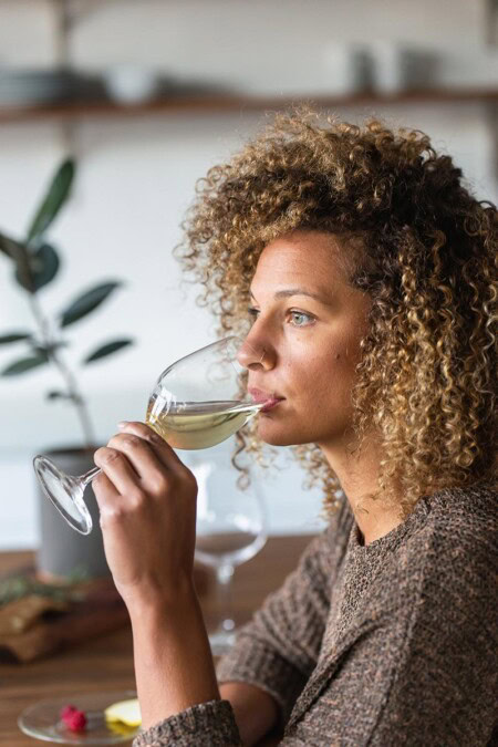 A young woman unwinds from her day as she sips on a glass of a refreshing glass of Riesling from Oregon's Willamette Valley.