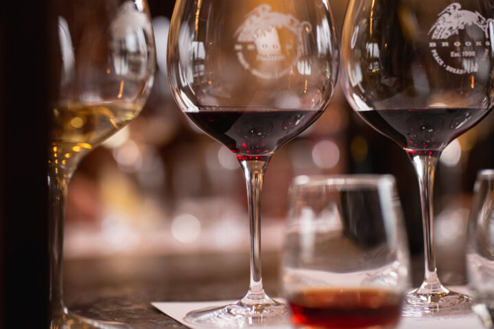 A flight of wine in stemmed glasses includes a glass of white wine, two glasses of red wine, and a small stemless glass of an aged red wine to help a taster learn how to describe wine.