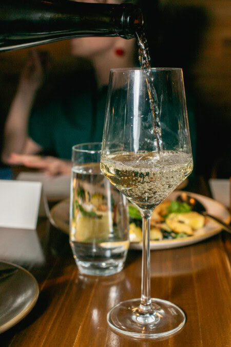 A glass of while non-alcoholic wine is poured at a dinner party.