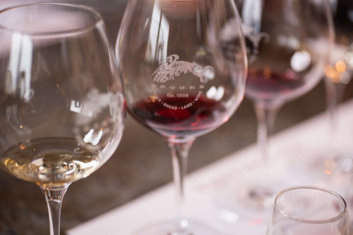 A flight of red and white wines rest on a tasting mat for sommeliers and wine enthusiasts to taste, describe, and assign quality based on the presence or absence of faults.