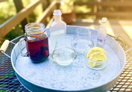 A metal tray presents the four elements of wine structure for students to taste: tannins in black tea, acidity in lemon wedges, sweetness in simple syrup, and alcohol in a shot of vodka.